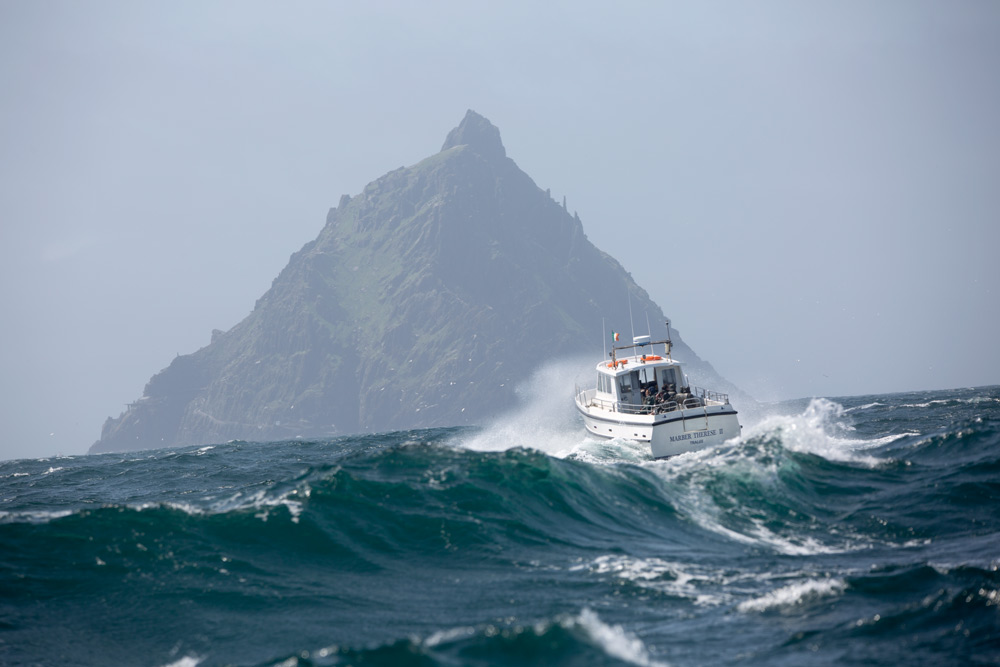 Boat on wave with Skellig Michael in the background